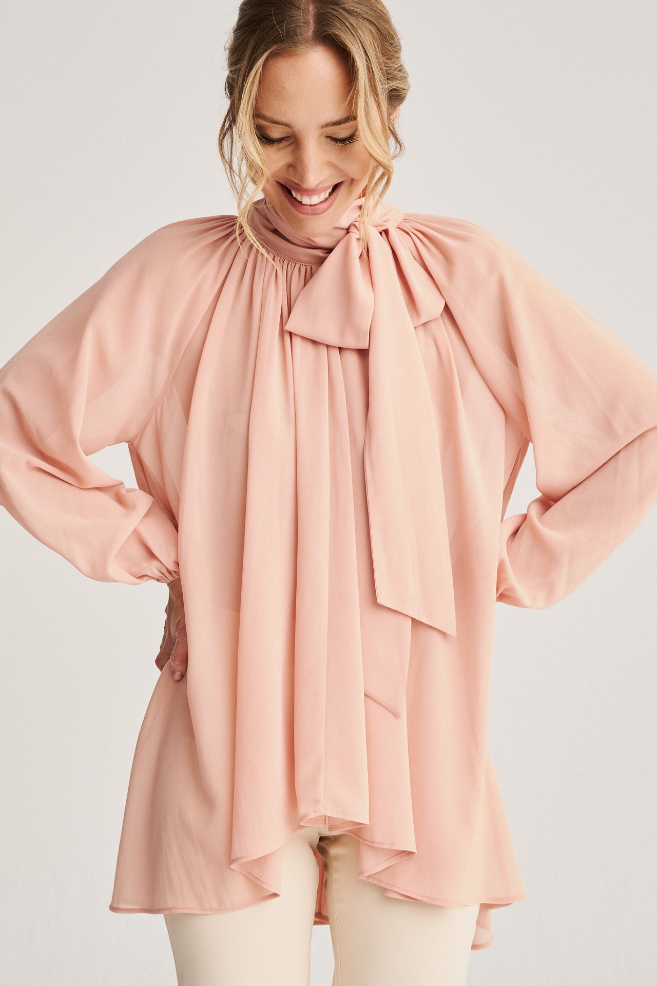 Top de gasa rosa maquillaje con mangas abullonadas, lazada en el cuello y largo asimétrico, perfecto para un look sofisticado.