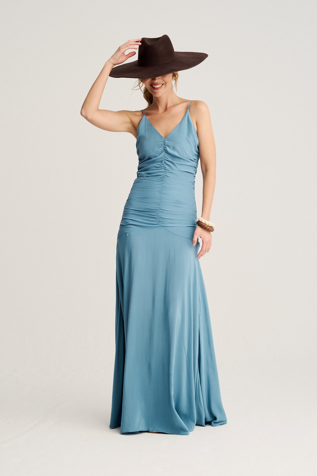 Vestido azul elegante con frunces en el cuerpo, tirantes multiposiciones y corte asimétrico en la cadera.