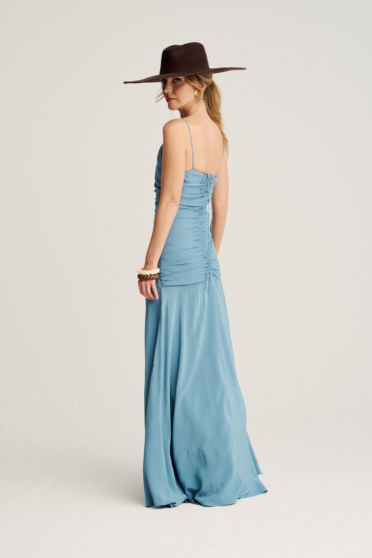 Vestido largo azul con tirantes multiposiciones, corte asimétrico y frunces que estilizan la figura.